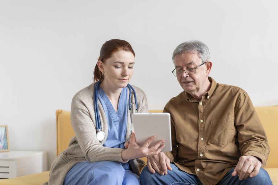 An older adult and a clinician reviewing information together on a tablet.